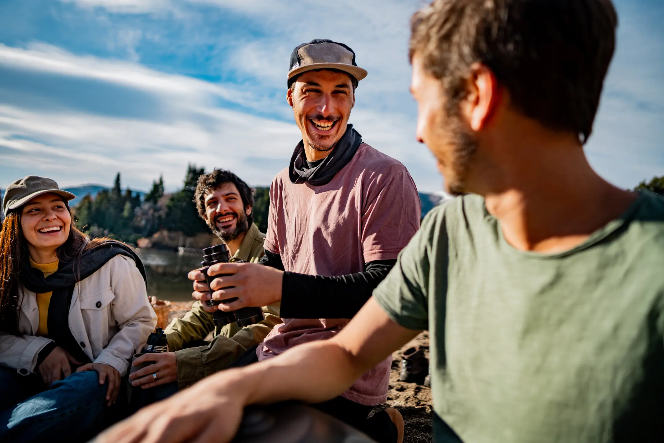 Group of friends laughing outdoors by lakeside