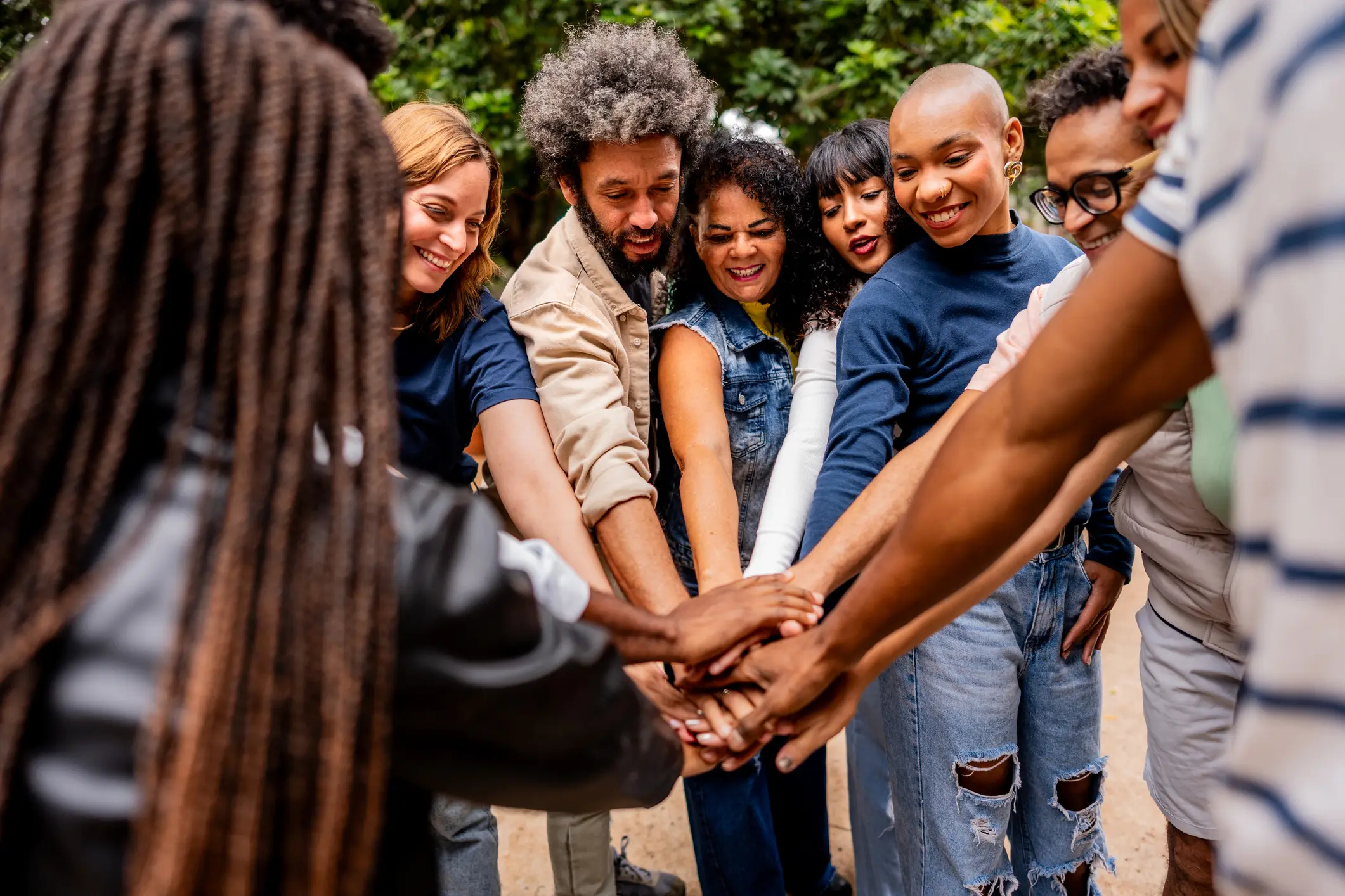Diverse group stacking hands in outdoor circle